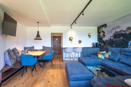sala de estar con sofá azul, mesa y sillas en Wolfgangsee Appartements, en Strobl