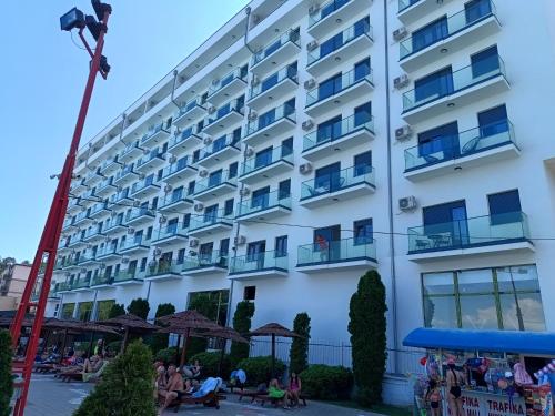 a large white building with people sitting outside of it at Apartman ELENA in Jagodina