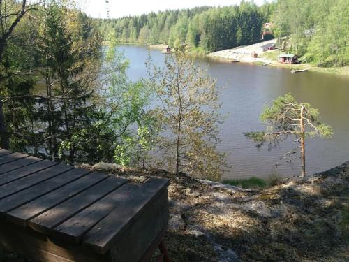 a wooden bench sitting on the side of a lake at Cottage / Mökki, unique summer cottage in Vihti
