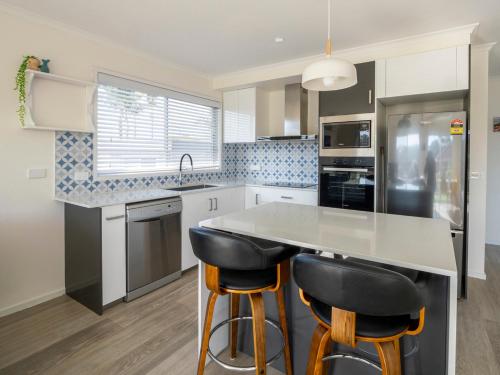 a kitchen with a counter and two bar stools at Mermaid Apartments in Merimbula
