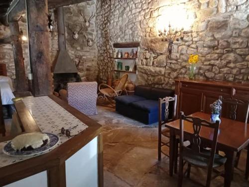 sala de estar con mesa y pared de piedra en El Refugio de Molinos de Razón., en Molinos de Razón