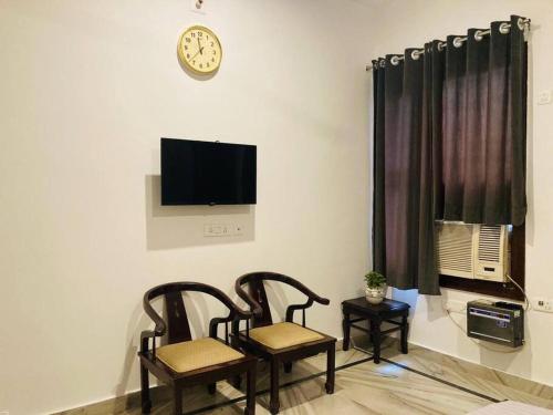 a living room with two chairs and a clock on the wall at Zoeys Homestay - 1BHK with Free Breakfast in Jammu