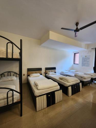 a room with three bunk beds and a ceiling at All Seasons Guest House I Rooms & Dorms in Madgaon