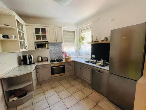 a kitchen with white cabinets and a stainless steel refrigerator at Klebi’s apartmanház in Balatonföldvár