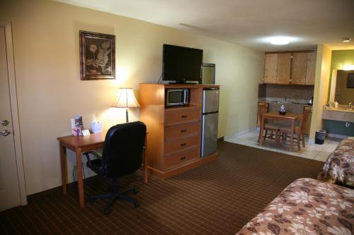a hotel room with a bed and a desk with a television at Coach Light Inn in Brenham