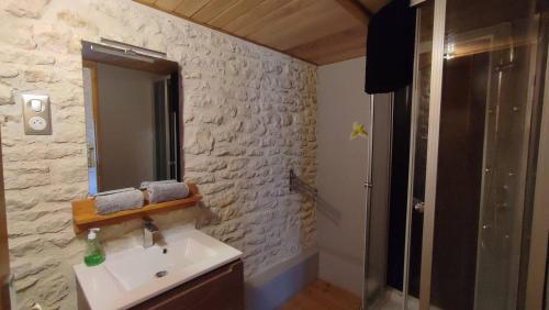 La salle de bains est pourvue d'un lavabo et d'un mur en pierre. dans l'établissement Le Haut Fontaine : gîte 4/5 pers. ou site entier 9 pers, à Saint-Georges-lès-Baillargeaux