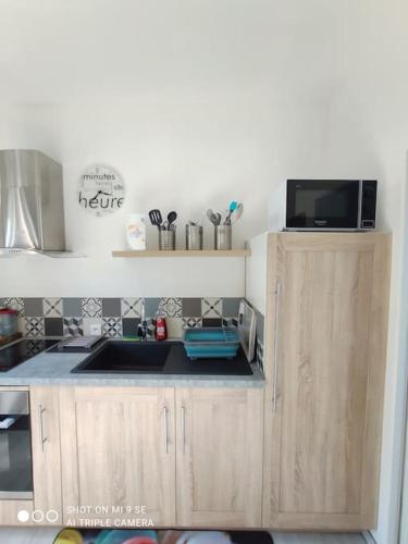 une cuisine avec un évier et un micro-ondes dans l'établissement Studio Tribord Le Tréport - vue mer & falaises, au Tréport
