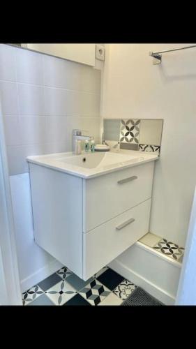 La salle de bains est pourvue d'un lavabo blanc et de carrelage. dans l'établissement Studio Tribord Le Tréport - vue mer & falaises, au Tréport