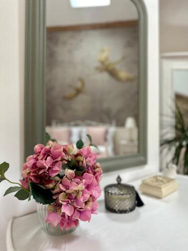 a vase of pink flowers on a table in front of a mirror at Figtrees in Margueron