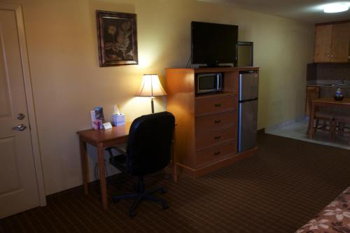 a hotel room with a desk with a chair and a television at Coach Light Inn in Brenham