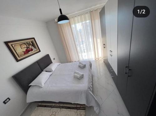 een slaapkamer met een groot bed met witte lakens bij Best Apartments in Elbasan