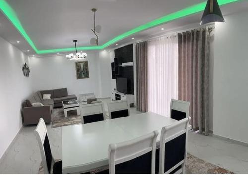 een eetkamer met een witte tafel en groene verlichting bij Best Apartments in Elbasan