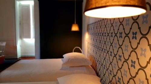 a bedroom with a bed with white sheets and a lamp at A Casa do Tenente in Faro