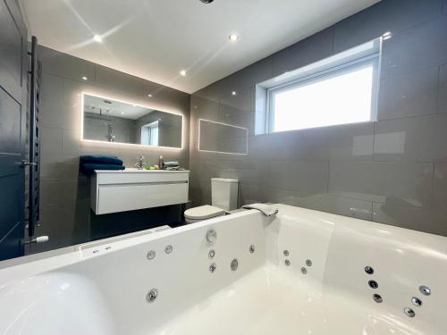 Un baño con una gran bañera blanca y un lavabo. en Farne Island rooms, en Seahouses