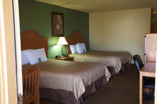 two beds in a hotel room with green walls at Coach Light Inn in Brenham