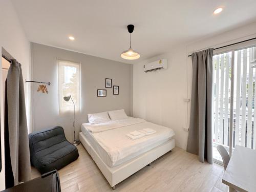 a bedroom with a bed and a chair and a window at Na Ekkamai Residence in Bangkok