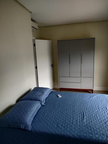 a bedroom with a blue bed and a white cabinet at Praia de Palmas - Aconchegante e Completo in Governador Celso Ramos