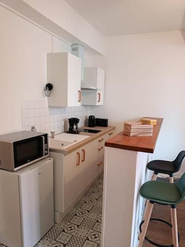 - une petite cuisine avec des placards blancs et un four micro-ondes dans l'établissement La garçonnière de Gégé, à Tournus