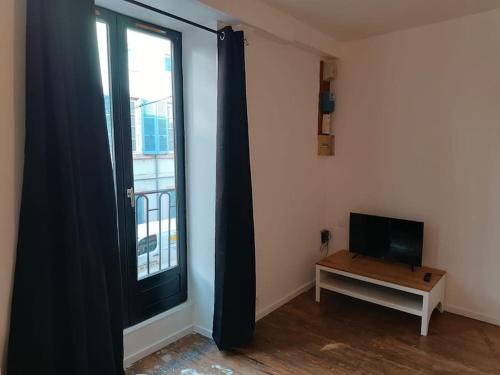 Cette chambre dispose d'une télévision, d'une table et d'une fenêtre. dans l'établissement La garçonnière de Gégé, à Tournus