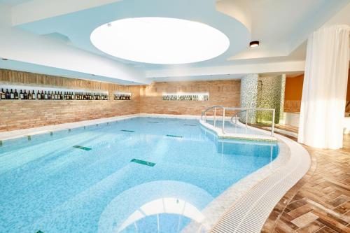 een groot zwembad in een hotel met een groot plafond bij Crocus Gere Bor Hotel Resort & Wine Spa in Villány