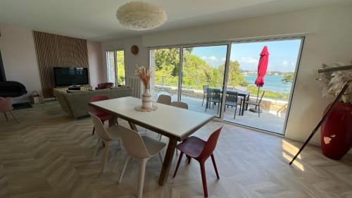 - un salon avec une table et des chaises et une vue sur l'océan dans l'établissement La maison sur la Ria _ 8 voyageurs, à Plouhinec