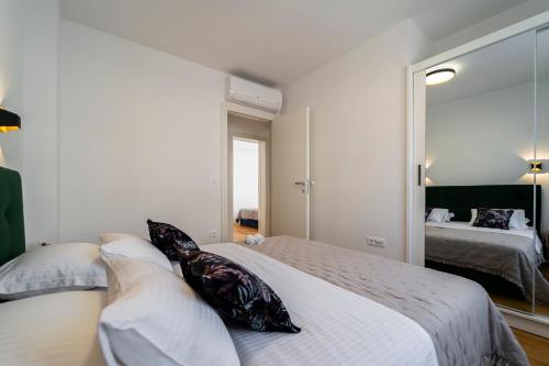 a bedroom with a bed with pillows and a mirror at Apartment Skyline Retreat in Zadar