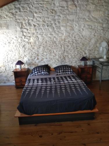 une chambre avec un lit et un mur en pierre dans l'établissement gîte 4 chambres à Cognac, à Cognac