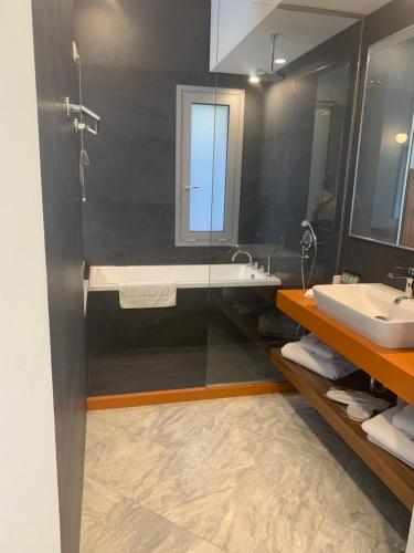 ein Badezimmer mit einer Badewanne, einem Waschbecken und einem Spiegel in der Unterkunft Petra Hotel in Agia Galini