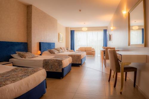 a hotel room with four beds and a table and chairs at Grand Karot Hotel in Yalova