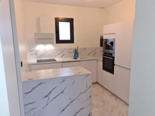 a white kitchen with marble counter tops and a window at Magnifique appart avec jaccuzi in Criel-sur-Mer