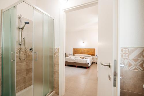 a bathroom with a shower and a bedroom at Domo Mediterranea Affittacamere-Guest House in SantʼAntìoco