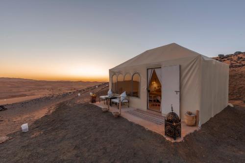 ein Zelt in der Wüste mit Sonnenuntergang im Hintergrund in der Unterkunft Soleil Camp & Camel Trekking in Merzouga