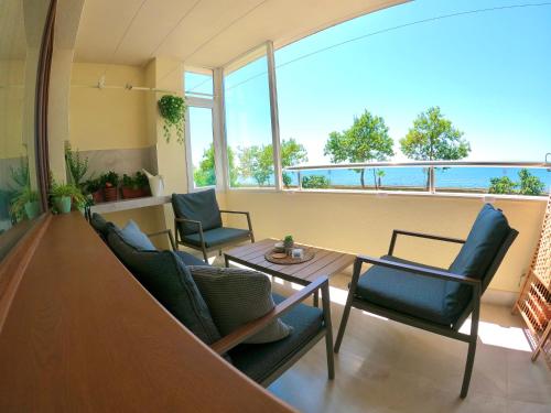 a room with chairs and a table with a view of the ocean at Sunset Yavorov Pomorie in Pomorie