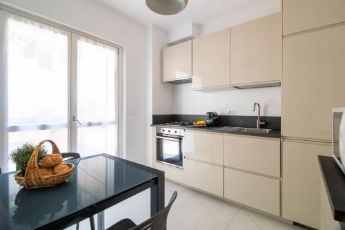 a kitchen with white cabinets and a glass table at Elios by PortofinoHomes in Portofino