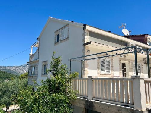 a white house with a balcony with a fence at Apartmani Luka in Korčula