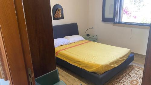 - une petite chambre avec un lit et une couverture jaune dans l'établissement Casa vacanze villa maresette, à Marsala