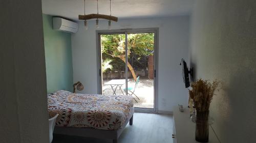 1 dormitorio con 1 cama y puerta a un patio en Grand jardin, plage, agréable, hôte reactif, en Saint-Cyprien