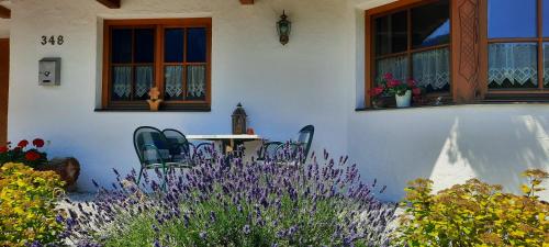 a white house with a table and purple flowers at Appartement Margreiter in Niederau