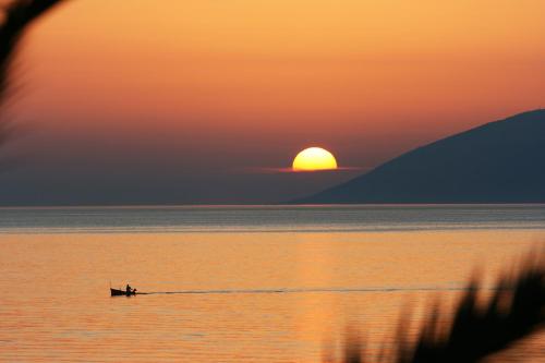 a person in a boat in the water at sunset at Apartment Dubravka in Podgora