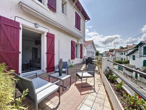 eine Terrasse mit Stühlen und Tischen in einem Gebäude mit roten Türen in der Unterkunft Appartement de charme Erdizka in Bayonne