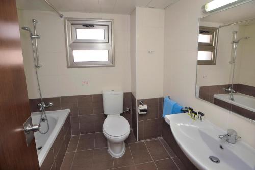 a bathroom with a toilet and a tub and a sink at Euronapa Hotel Apartments in Ayia Napa