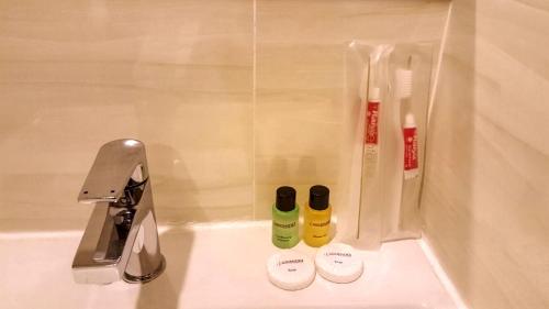um lavatório de casa de banho com duas garrafas de escovas de dentes e uma torneira em Crescendo Boutique Hotel em Nusajaya