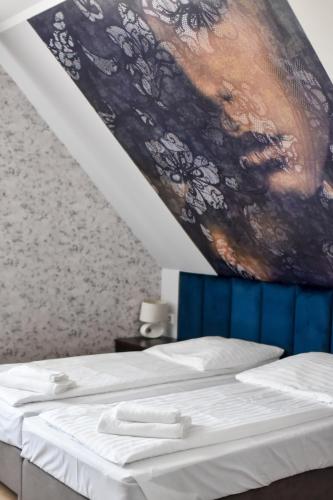 a bedroom with two beds and a painting on the wall at Jarzębinowy Resort & SPA in Braniewo