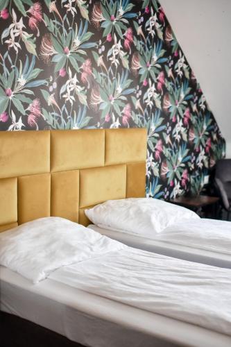 a bed with a wooden headboard and a floral wallpaper at Jarzębinowy Resort & SPA in Braniewo