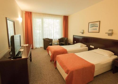 a hotel room with two beds and a flat screen tv at Hotel Divesta - self check in in Varna City