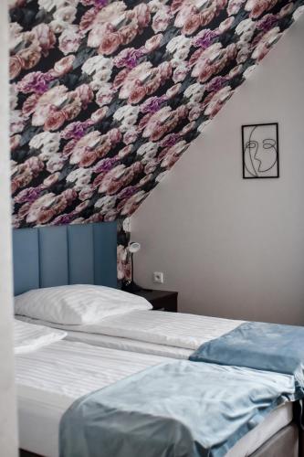 a bedroom with a flower patterned wall above a bed at Jarzębinowy Resort & SPA in Braniewo