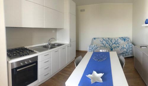 a kitchen with a table and a sink and a stove at LE COLONIE Apartments in Porto Cesareo