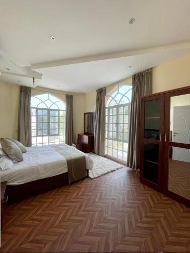 a bedroom with a bed and two windows at Deluxe Apartment in Muscat