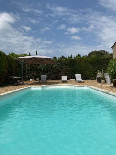 une grande piscine bleue avec un parasol et des chaises dans l'établissement Maison avec ses 2 terrasses et sa piscine, à Eyragues