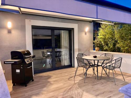 eine Terrasse mit einem Grill, einem Tisch und Stühlen in der Unterkunft Maison avec ses 2 terrasses et sa piscine in Eyragues